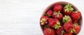 Fresh organic strawberries in a pink ceramic bowl on white wooden surface, overhead view. From above, flat lay, top view Royalty Free Stock Photo