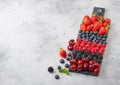 Fresh organic summer berries mix on black marble board on light kitchen table background. Raspberries, strawberries, blueberries, Royalty Free Stock Photo