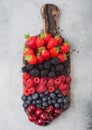 Fresh organic summer berries mix on vintage wooden chopping board on light kitchen table background. Raspberries, strawberries, Royalty Free Stock Photo