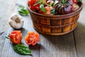 Fresh Organic Tomatoes in a basket and basil with garlik on a wooden table. Royalty Free Stock Photo