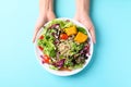 Fresh organic vegetables with quinoa salad holding by hand on color background Royalty Free Stock Photo