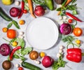 Fresh organic vegetables and seasoning ingredients for tasty vegetarian cooking around plate Royalty Free Stock Photo