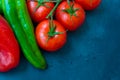 Fresh organic vegetables, tomatoes on a vine, green italian and red bell peppers, dark blue background, styled image, top view Royalty Free Stock Photo