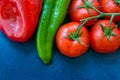 Fresh organic vegetables, tomatoes on a vine, green italian and red bell peppers, water drops, dark blue background, styled image Royalty Free Stock Photo