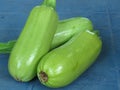 Fresh organic vibrant green courgette / marrows on blue background.