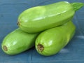 Fresh organic vibrant green courgette / marrows on blue background.