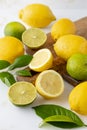 Fresh organic yellow lemon and green lime fruits whole and sliced with citrus leaves on wooden cutting board Royalty Free Stock Photo
