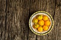 Fresh, organic yellow tomatoes on yellow plate over rustic wooden background with copy space. Flat lay Royalty Free Stock Photo