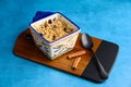 Fresh out of the oven blueberry crumble, in a single serving bowl with fresh cinnamon, on a medium blue background