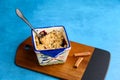 Fresh out of the oven blueberry crumble, in a single serving bowl with fresh cinnamon, on a medium blue background