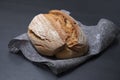 Fresh oval bread on a gray material with a black background. Appetizing bread close-up