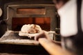 Fresh from the oven. a male baker removing freshly baked bread from the oven.