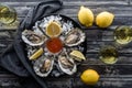 Fresh oysters on a plate of ice with lemon wedges served with glasses of white wine. Royalty Free Stock Photo