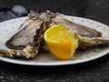 Fresh Oysters in plate, lemon, shells on marble. Delicacy super food, rich in antioxidants, vitamin, zinc