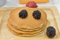 Fresh pancakes many color stacked layered with orange on wooden plate
