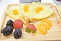 Fresh pancakes with strawberry, black berries and orange on wooden plate