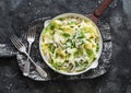 Fresh papardelle with chicken ragout , green peas and fennel in pan on wooden rustic board on dark background, top view