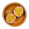 Fresh passion fruit cut in two halves, in a wooden bowl