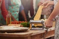 Fresh pasta is the best pasta. a woman making fresh pasta with people standing in the background. Royalty Free Stock Photo