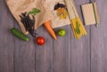 Fresh pasta ingredients in eco paper bags - spaghetti pasta, carrot, basil, tomato and other vegetables, notepad for recipe Royalty Free Stock Photo