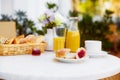 Fresh pastries, coffee, jam, a decanter and a glass of orange juice stand on a table decorated with a bouquet of delicate flowers Royalty Free Stock Photo