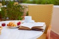 Fresh pastries, coffee, jam, and an open book are arranged on the table. Breakfast on the terrace with an interesting book