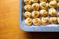 Fresh pastries in a metal gray baking tray. The corner of the baking tray in small buns, baking in shape of a rose or Royalty Free Stock Photo