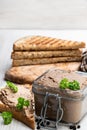 Fresh pate in glass jar with toasted bread on white wooden table