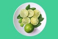 Fresh pattern with slices of lime and green mint leaves on white plate and neo mint color background. Royalty Free Stock Photo