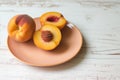 fresh peach halves on a peachcolored ceramic plate with a white table Royalty Free Stock Photo