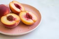 fresh peach halves on a peachcolored ceramic plate with a white table Royalty Free Stock Photo