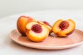 fresh peach halves on a peachcolored ceramic plate with a white table Royalty Free Stock Photo