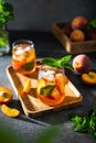 Fresh Peach iced tea. Iced tea with peach slices, mint and ice cubes on a wooden tray on dark background. Close up. Homemade Royalty Free Stock Photo