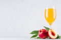 Fresh peach juice in elegance glass and ripe red nectarines with green leaves on soft white wood board. Royalty Free Stock Photo