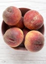 Fresh peaches  in a pink bowl over white wooden background, top view. From above, overhead Royalty Free Stock Photo