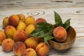 Ripe peaches in a wooden plate with leaves on the table Royalty Free Stock Photo