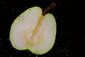 A fresh pear cut in half floats under water against a dark background with air bubbles Royalty Free Stock Photo