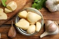 Fresh peeled garlic cloves in bowl and bulbs on wooden table, flat lay. Organic product Royalty Free Stock Photo