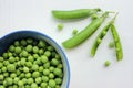 Fresh peeled green sugar snap peas in a bowl and open pods on a white wooden table background with copy space. Royalty Free Stock Photo