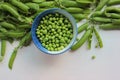 Fresh peeled green sugar snap peas in a bowl and open pods on a white wooden table background with copy space. Royalty Free Stock Photo