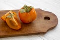 Fresh persimmon on a chopping board on white wooden background, side view. Close-up Royalty Free Stock Photo