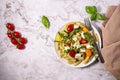 Fresh pesto pasta salad with different colours of cherry tomatoes and mozzarella.