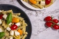 Fresh pesto pasta salad with different colours of cherry tomatoes and mozzarella.