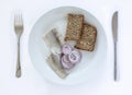 Fresh pickled herring on a plate with homebaked rustic seeded rye bread and onion rings. Scandinavian food. Top view with cutlery