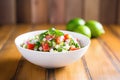 fresh pico de gallo in a white bowl on a wooden table Royalty Free Stock Photo