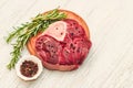 Fresh piece of meat large beef steak on the bone ossobuco with pepper, rosemary on the board.