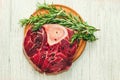 Fresh piece of meat large beef steak on the bone ossobuco with pepper, rosemary on the board.