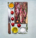 Fresh pieces of raw lamb on a chopping board, with herbs, spices, cherry tomatoes, lined rectangle on wooden rustic background top Royalty Free Stock Photo