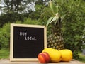 Fresh Pineapple with Asian Melons and Peach on Table With Buy Local Sign