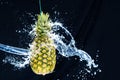 Fresh pineapple gets splashed with water on black background. Concept of summer, health and fun